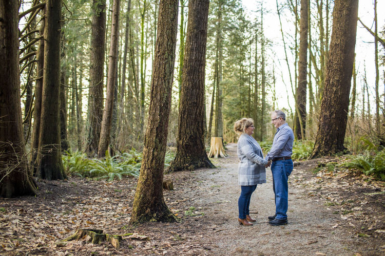 Older couple holding hands and looking at each other in the forest.
