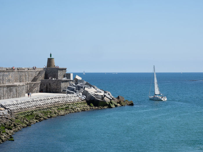 Sailboats in sea against clear blue sky