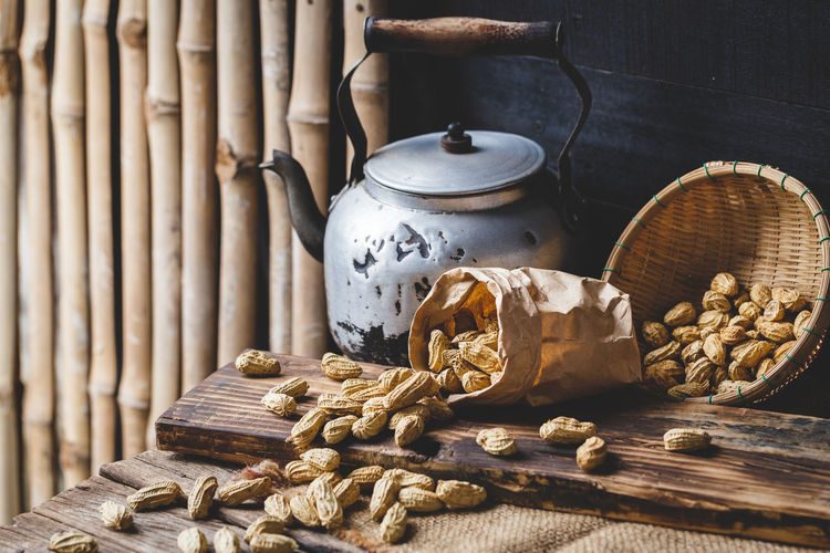 Close-up of peanuts in wicker containers with kettle on table