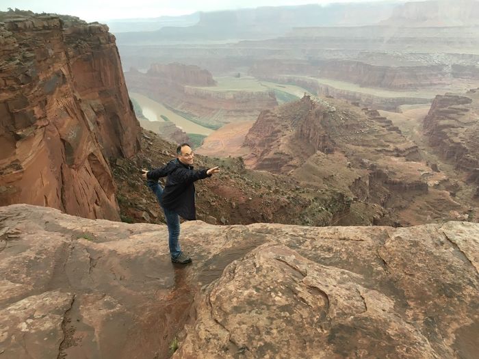High angle view of smiling man practicing bow pose at dead horse point state park