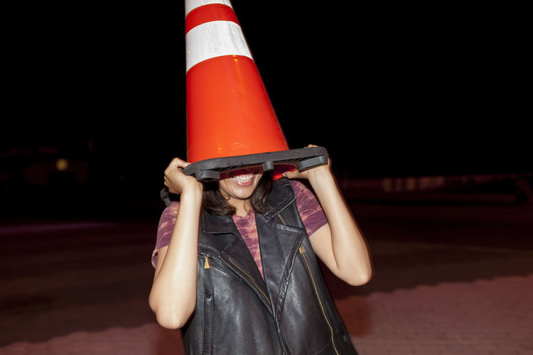 Playful young woman with a traffic cone on her head