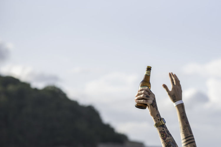 Cropped tattooed hand holding beer bottle