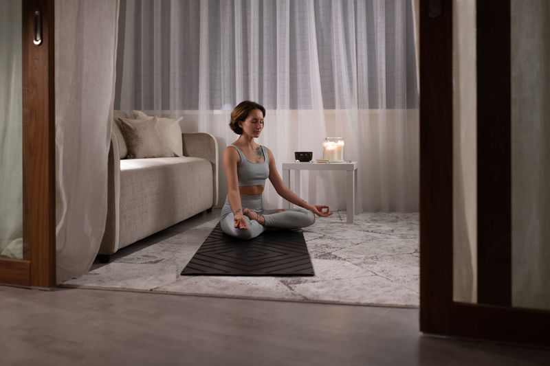 Young woman meditating in living room