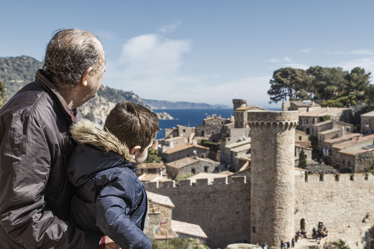 Grandson and grandfather looking at view of tossa de mar