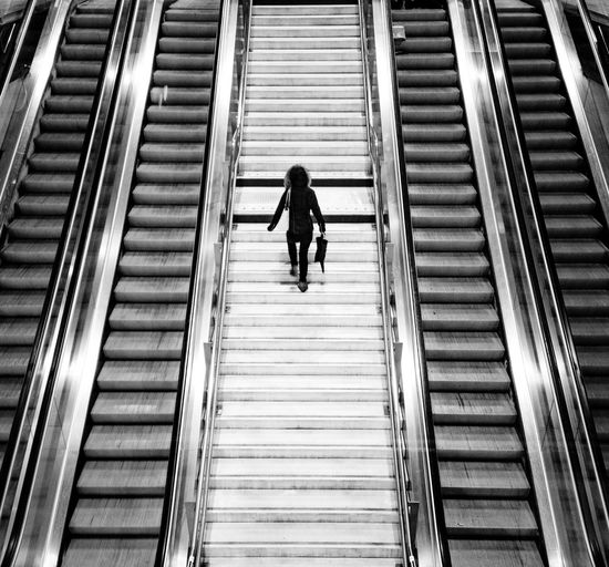 Rear view of woman walking on escalator