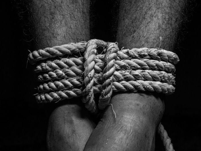 Close-up of hand holding rope against black background
