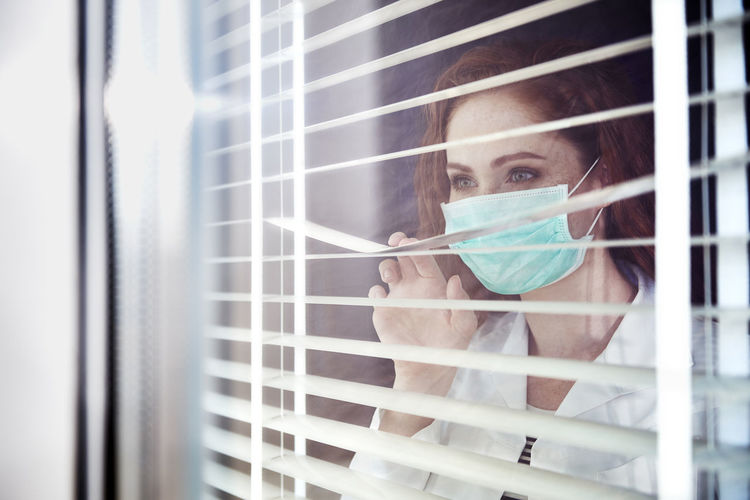 Close-up of doctor looking away through blinds