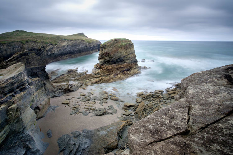 High angle view of sea and rocks against cloudy sky