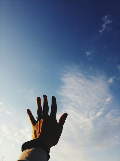 Low angle view of person hand against sky