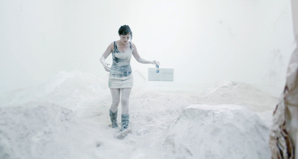Full length of messy artist walking amidst powdered plaster at workshop