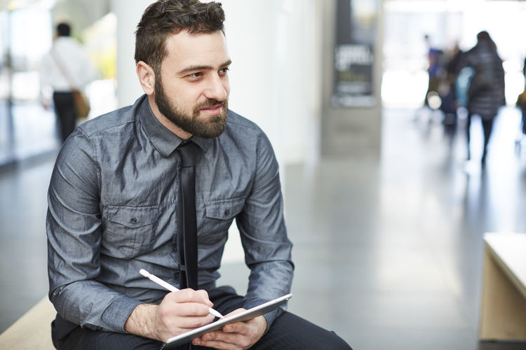 Businessman writing notes in diary while sitting at office