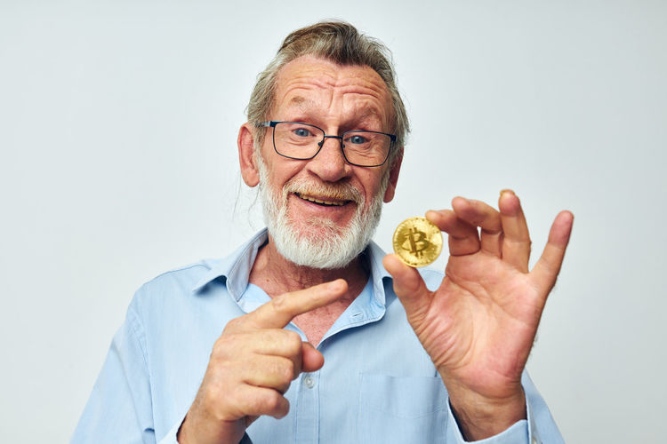 Senior man showing bitcoin against white background