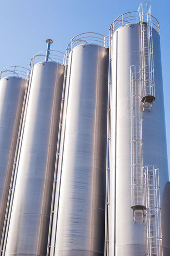 Low angle view of silos of factory against sky