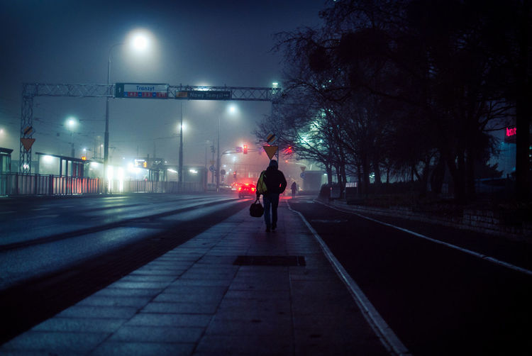 Rear view of man on road at night
