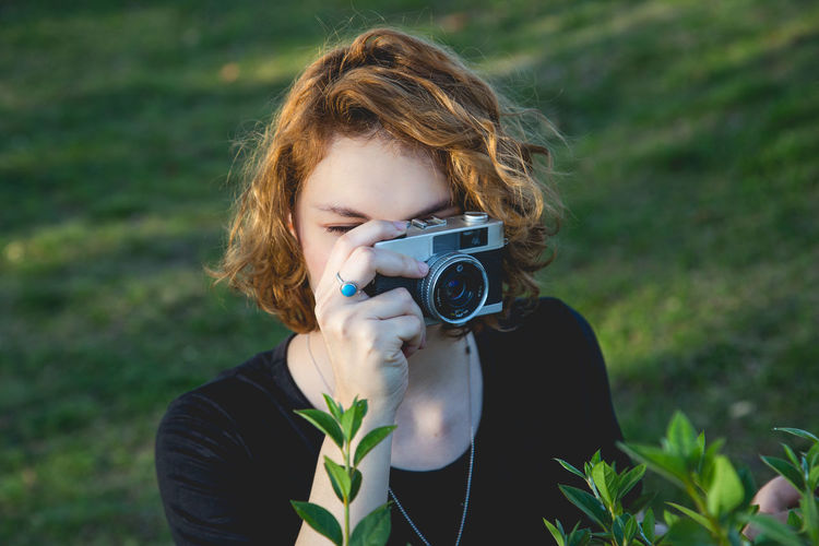 Portrait of woman photographing while standing outdoors