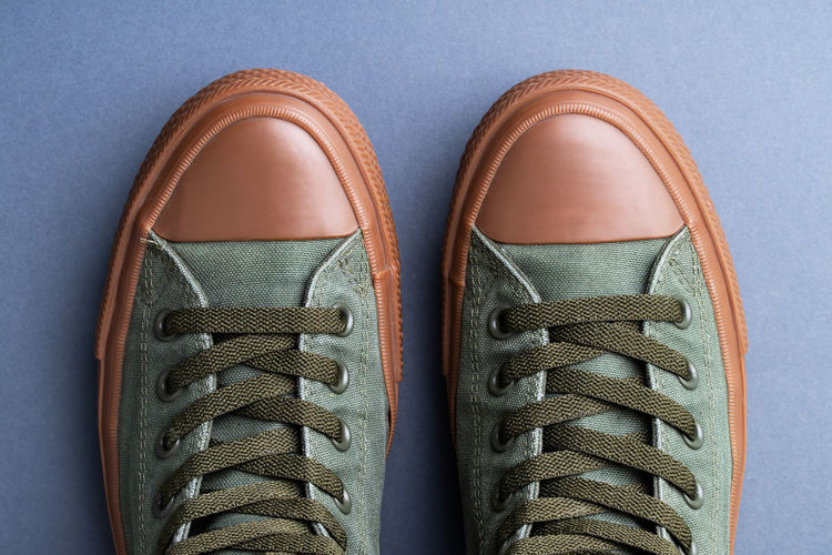 Low section of person wearing shoes standing against white background