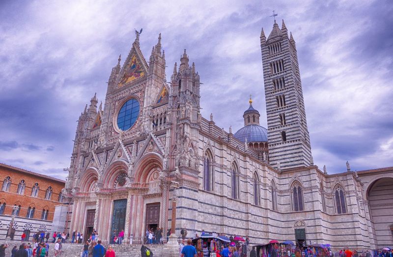 Low angle view of siena cathedral against cloudy sky in city