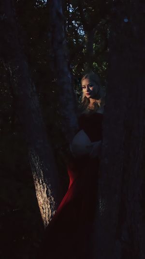 Woman standing by tree trunk in forest