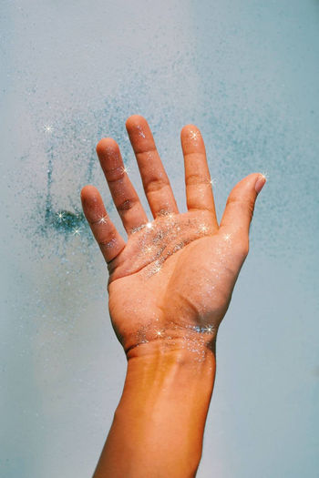 Close-up of hand with glitter on white background