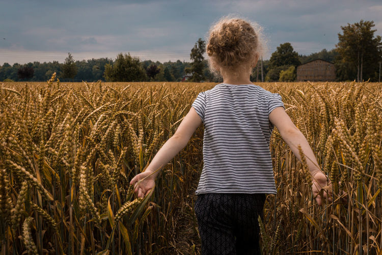 Rear view of girl standing on wheat field