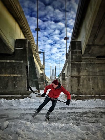 Man playing ice hockey in city during winter