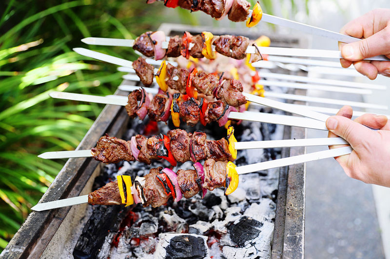 Midsection of person preparing food on barbecue grill