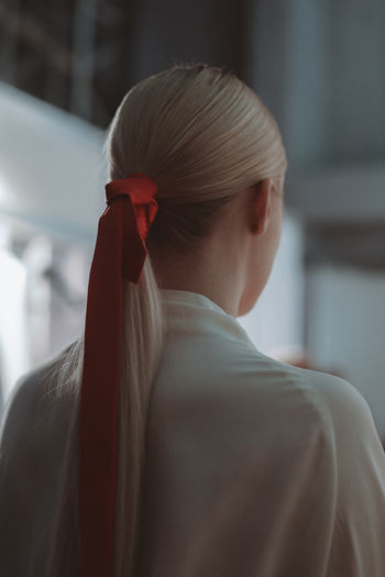 Female hairstyle of blonde hair elegant ponytail with red ribbon. back view