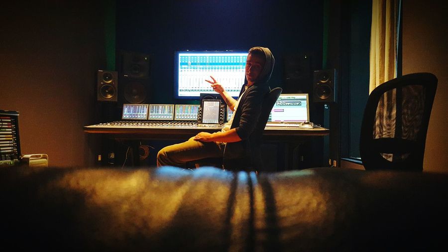 Portrait of musician showing peace sign while sitting in recording studio