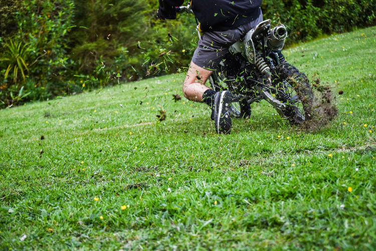 Low section of man riding motorcycle on grassy field