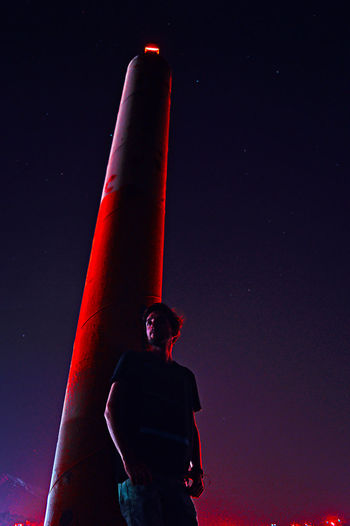 Low angle view of man standing against lighthouse at night