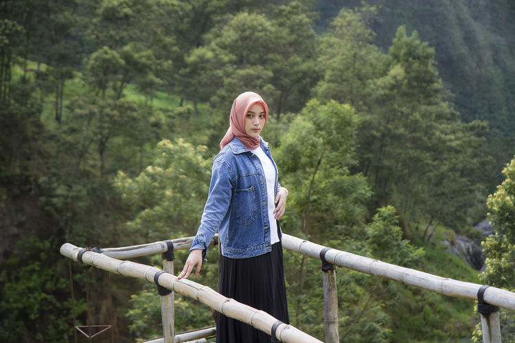 Asian muslim woman standing against trees in forest at kali talang, yogyakarta, indonesia