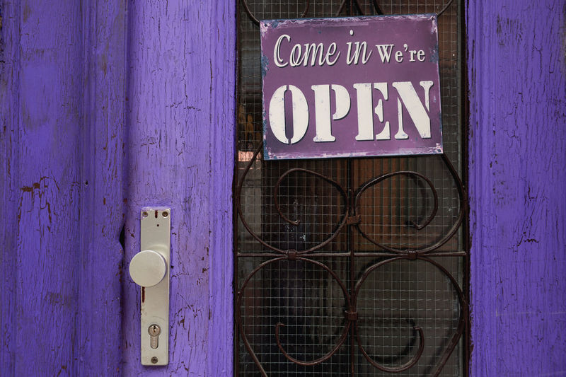 Open sign hanging on purple door