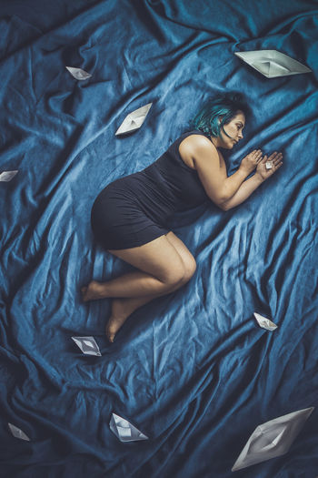 High angle view of woman resting on bed