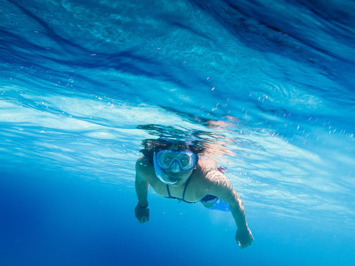 Portrait of woman swimming in blue sea