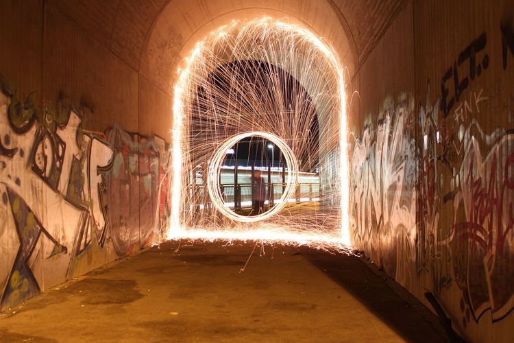 Man spinning wire wool in tunnel at night