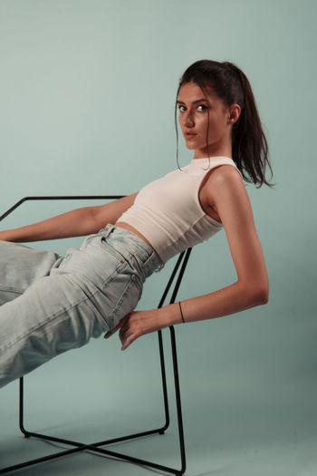 Portrait of woman sitting on chair against wall