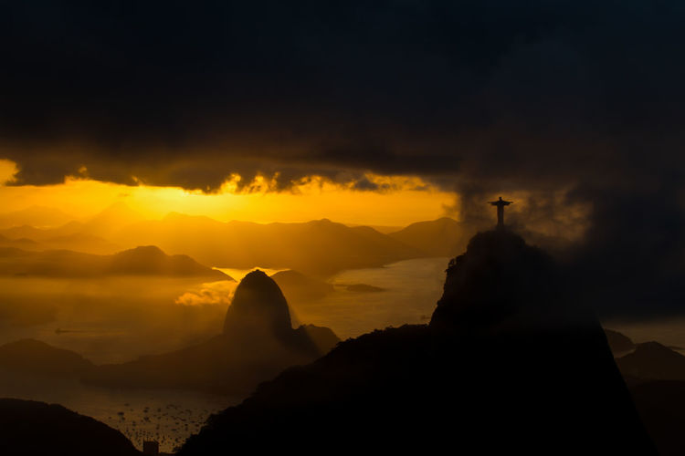 Silhouette rock formations against cloudy sky during sunset