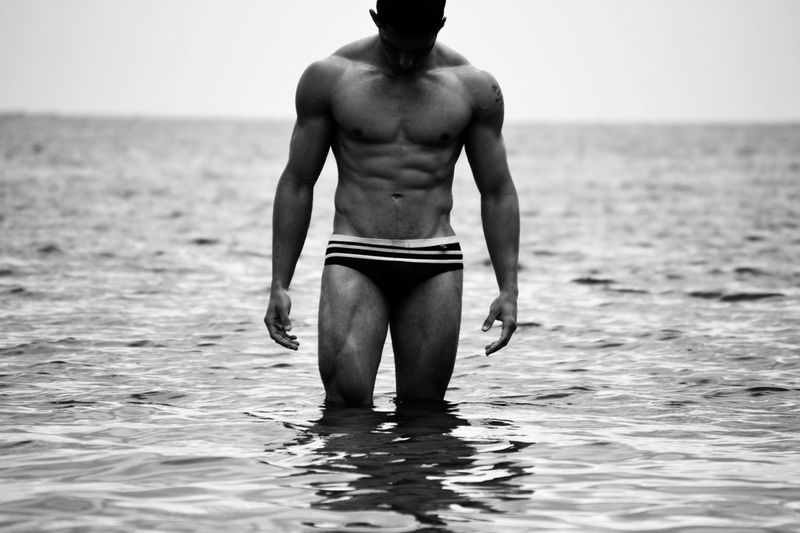 Shirtless man in underwear standing in sea