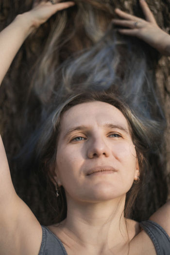 Close up adult woman lying on tree bark and looking at sky portrait picture