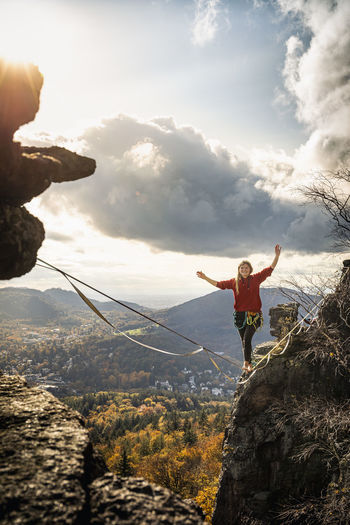 Woman with arms raised slacklining amidst mountains at baden-baden, germany