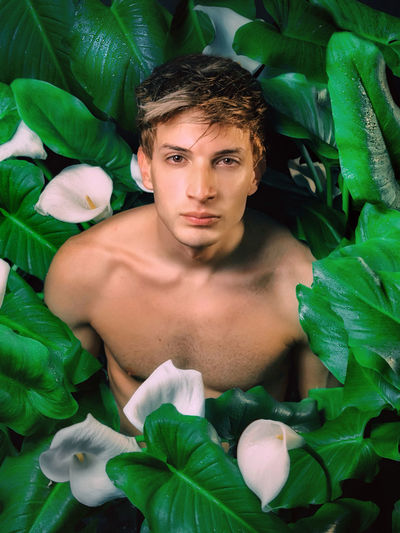 Portrait of young man with green leaves