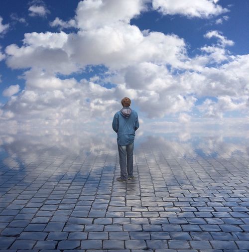 Full length of man standing on footpath against sky
