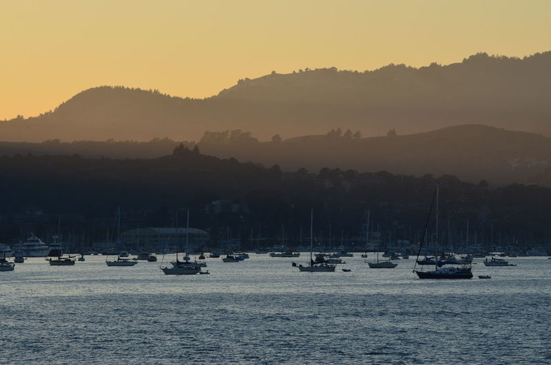 Silhouette sailboats in lake against sky during sunset