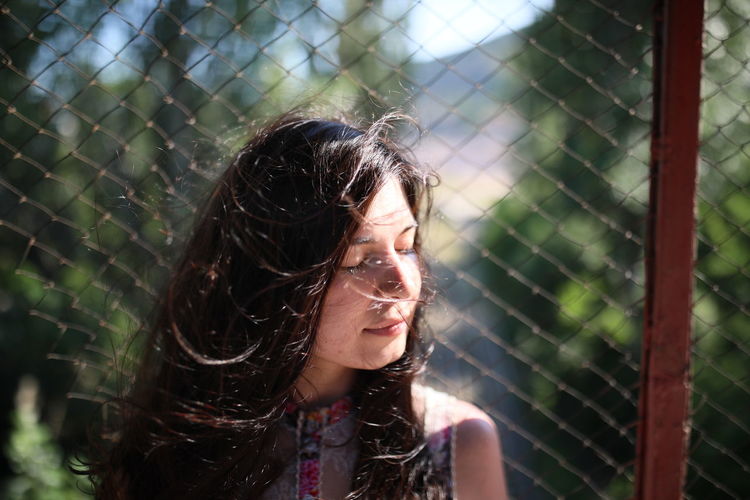 Portrait of young woman looking through fence