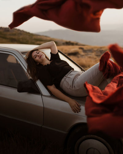 Woman in top of a car with blankets flowing in the wind