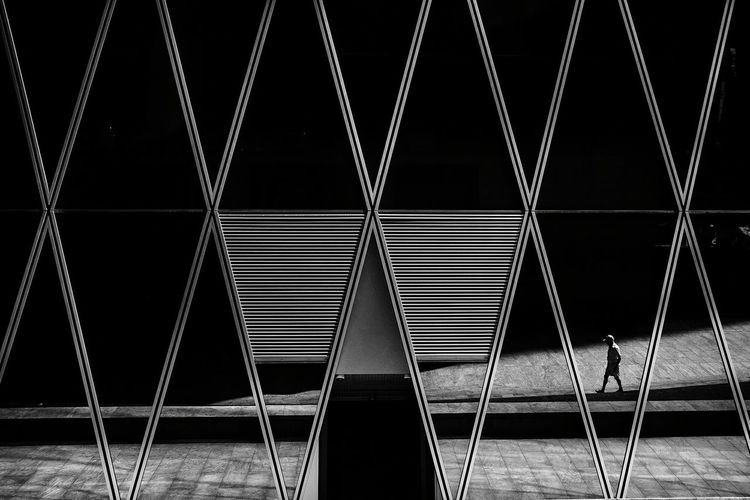 Boy walking at pedestrian zone reflecting on modern glass building