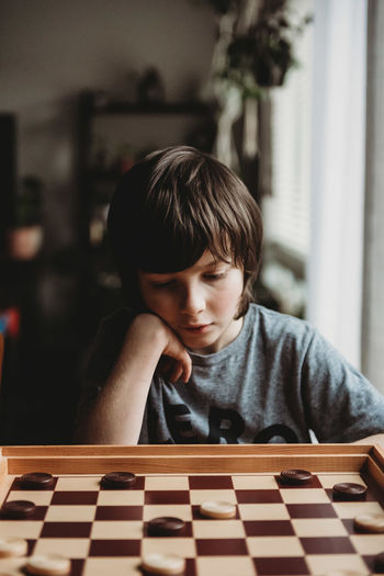 Thoughtful boy looking at chess board