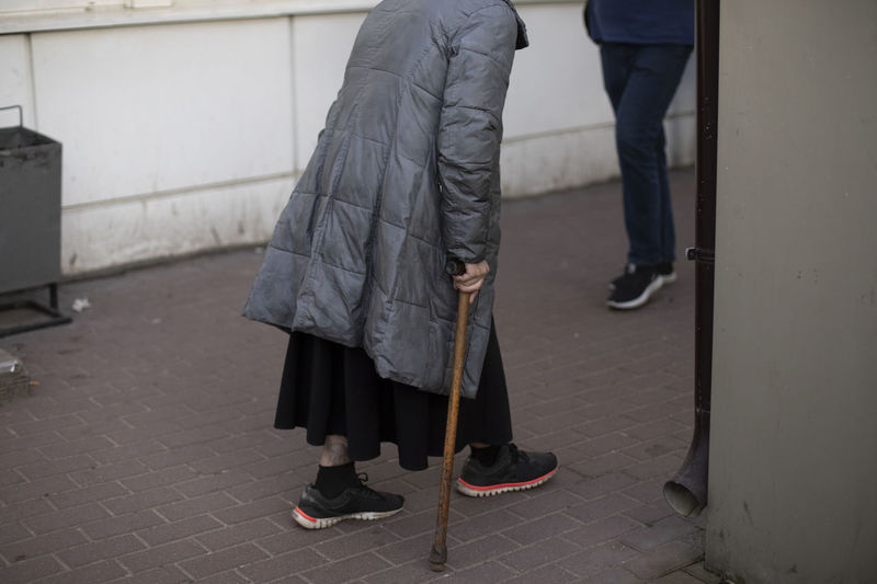 The old lady goes with a stick. a crutch in a woman's hand. pensioner on the street. 
