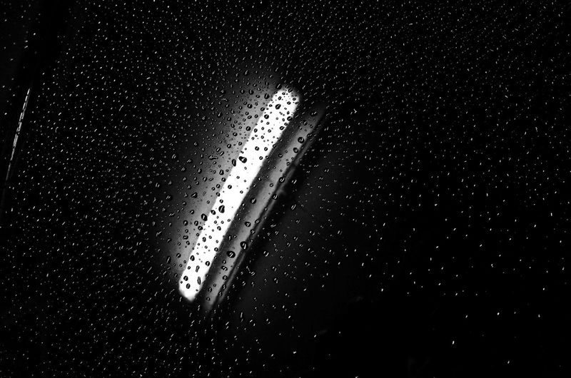 Close-up of water drops on car against black background