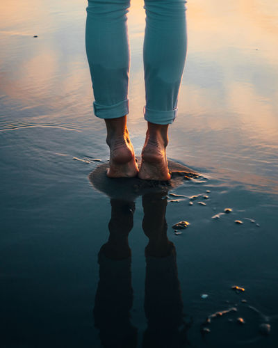 Low section of man standing on lake against sky